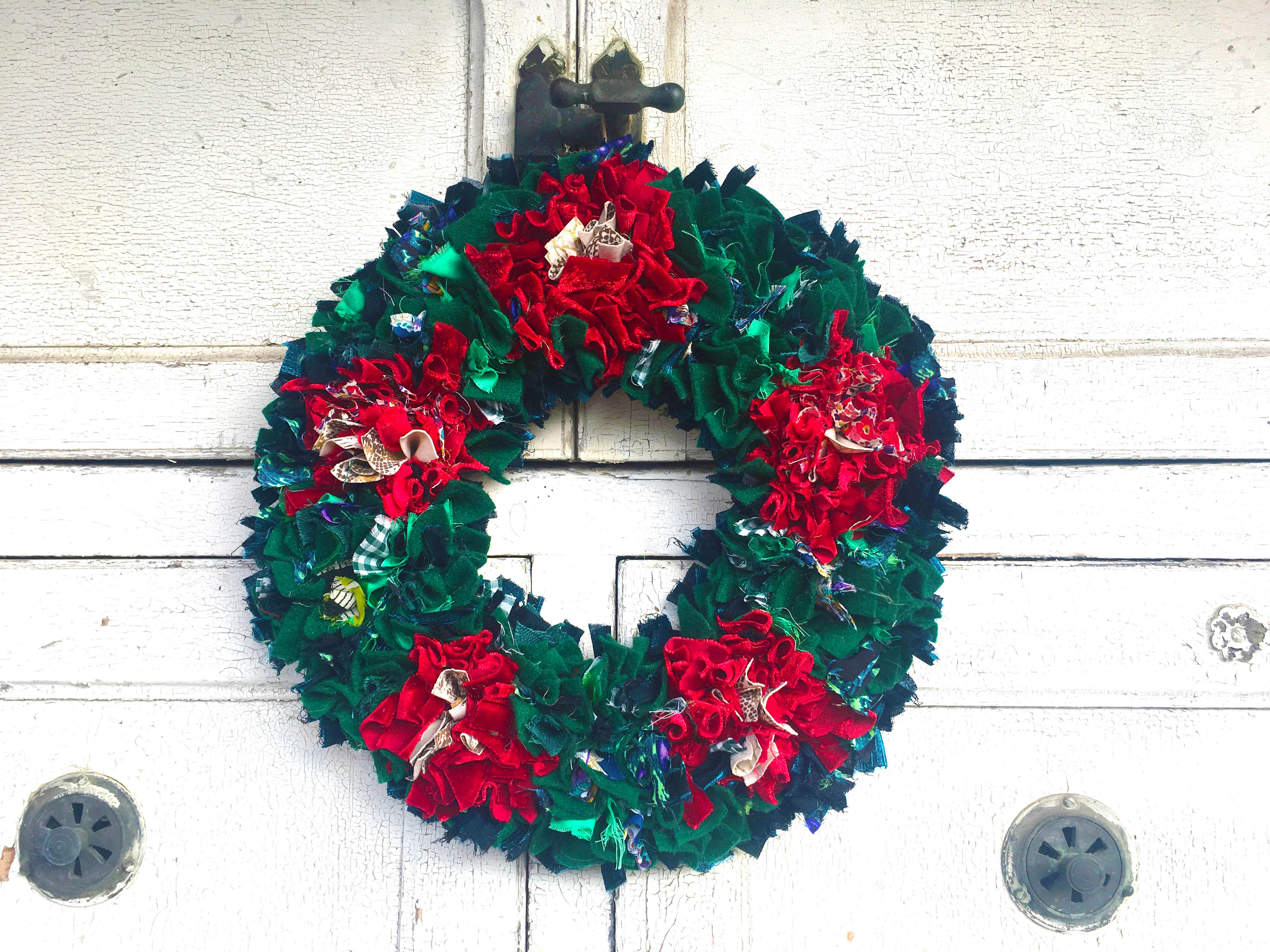 Traditional red and green rag rug christmas wreath made of old clothing with a rag rug spring tool