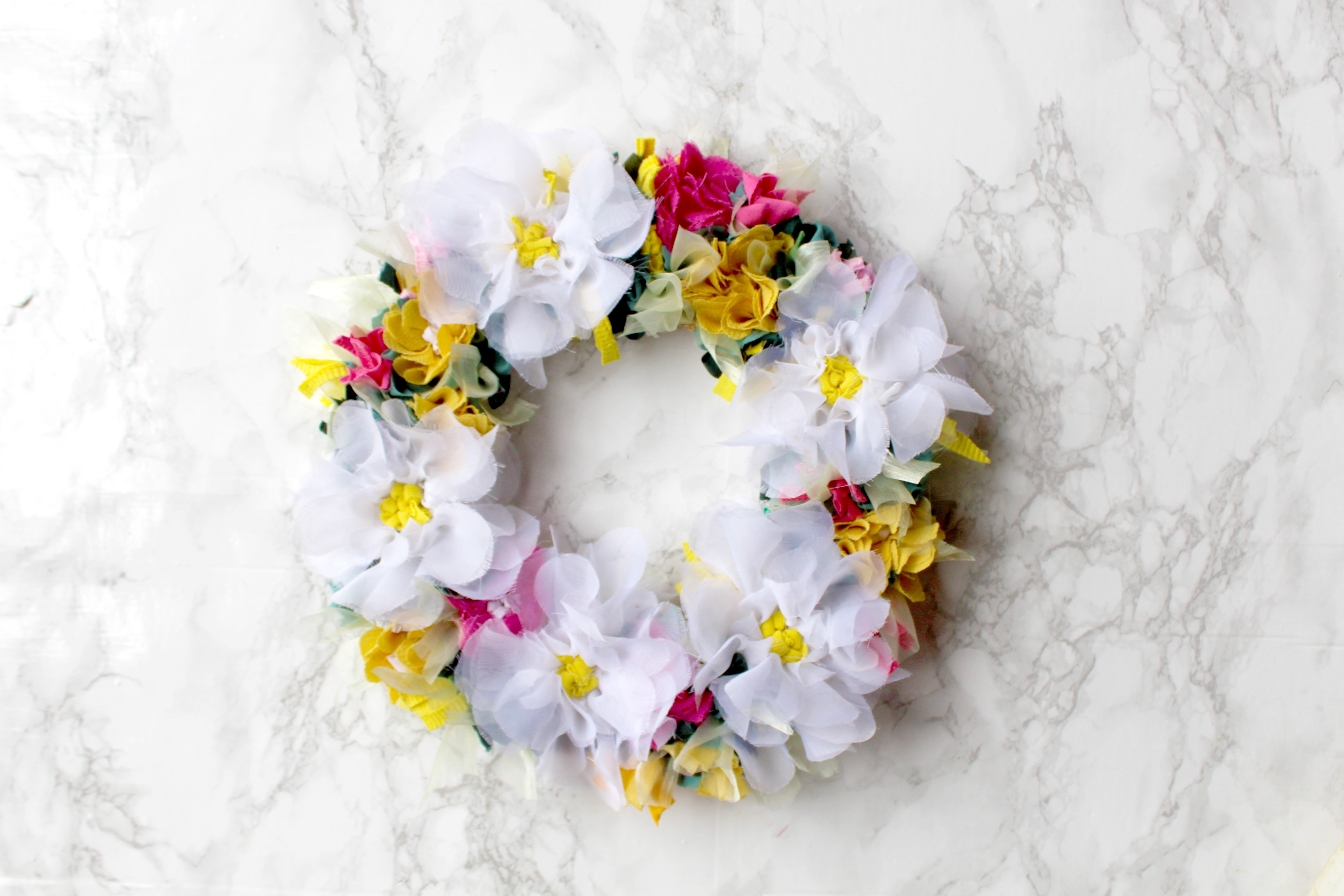 Ragged Life spring rag rug wreath made using recycled material with white flowers and pink and green foliage. 