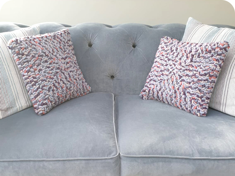 Purple hooked rag rug cushions on sofa