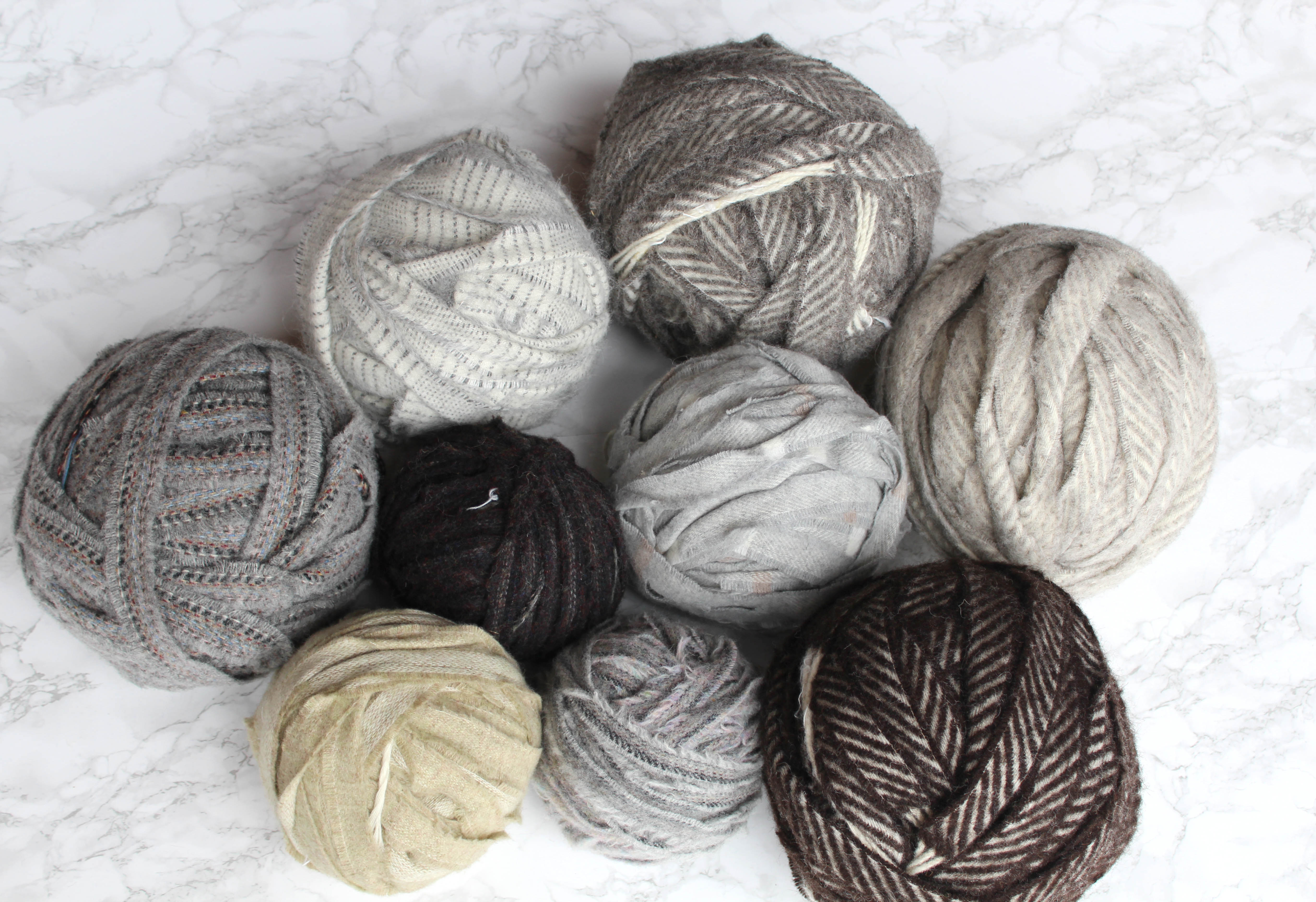 Grey, brown and cream balls of blanket yarn for rug making and knitting