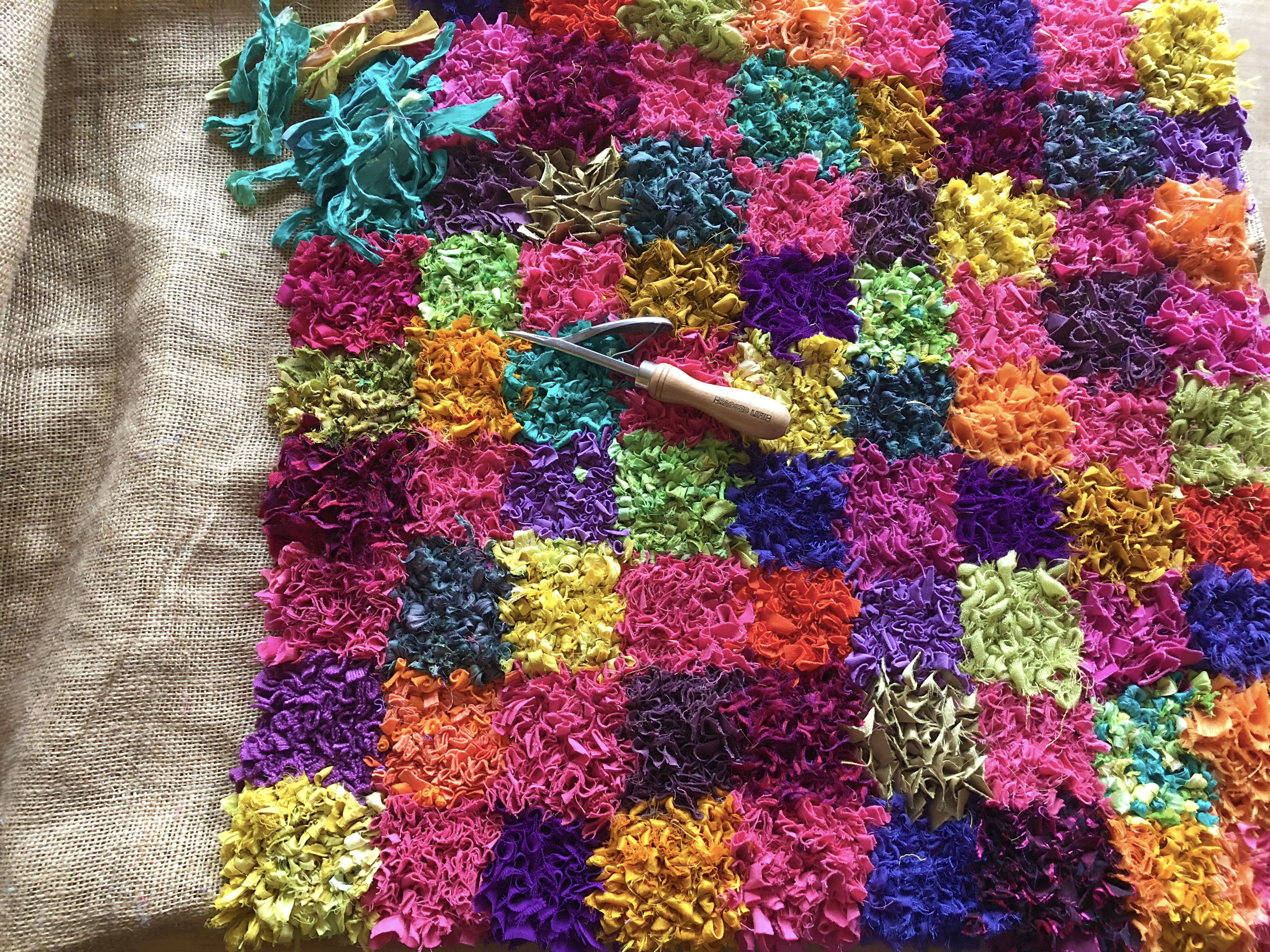 Partially made modern rag rug made using sari silk and recycled fabric in bright colours