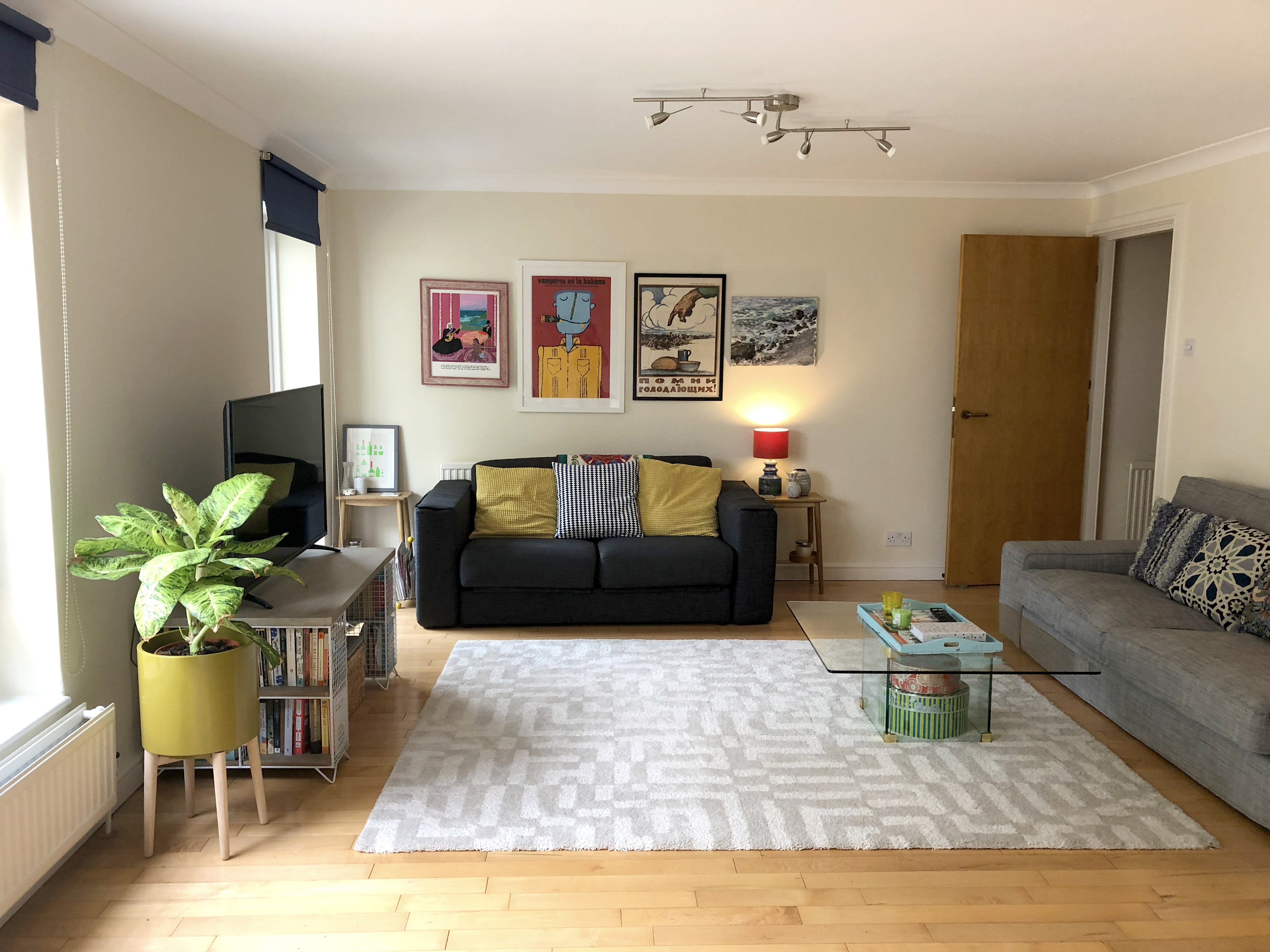 Colourful living room with big white and grey area rug and a glass coffee table