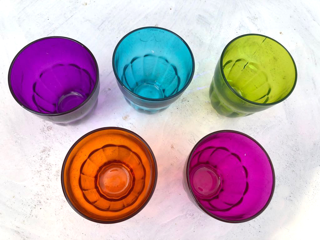 Colourful jewel coloured water glasses in purple, blue, orange, green and pink