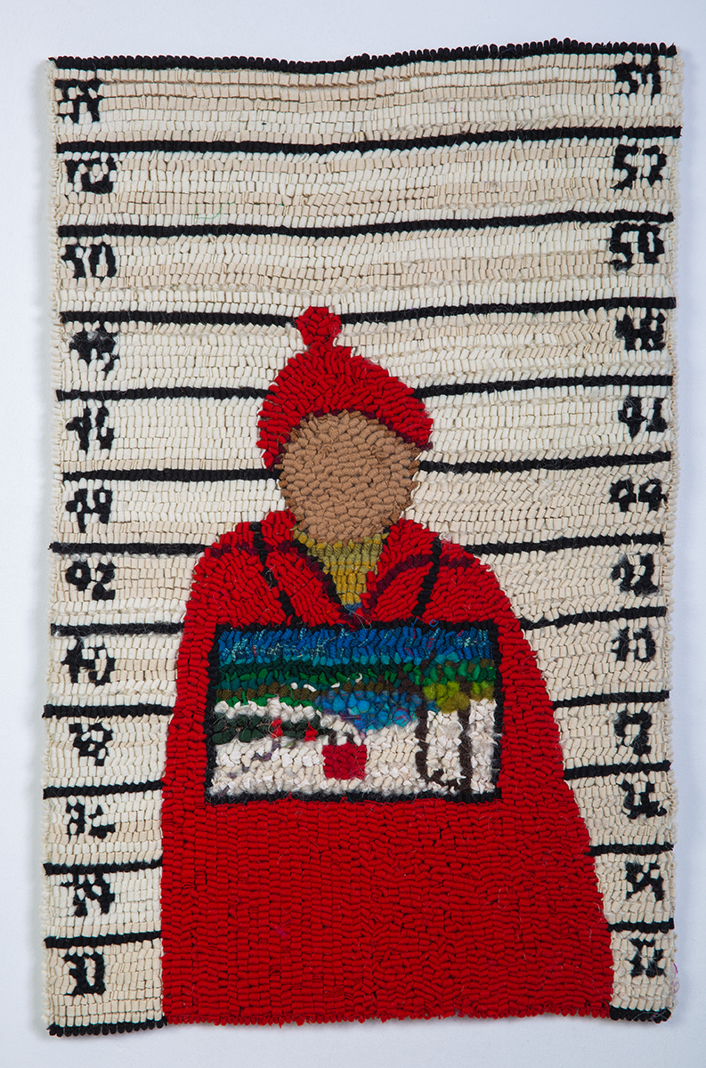 Textile art of a figure dressed in a red coat and hat agist a police line up board with a iece of art hanging around their neck by Laura Kenney