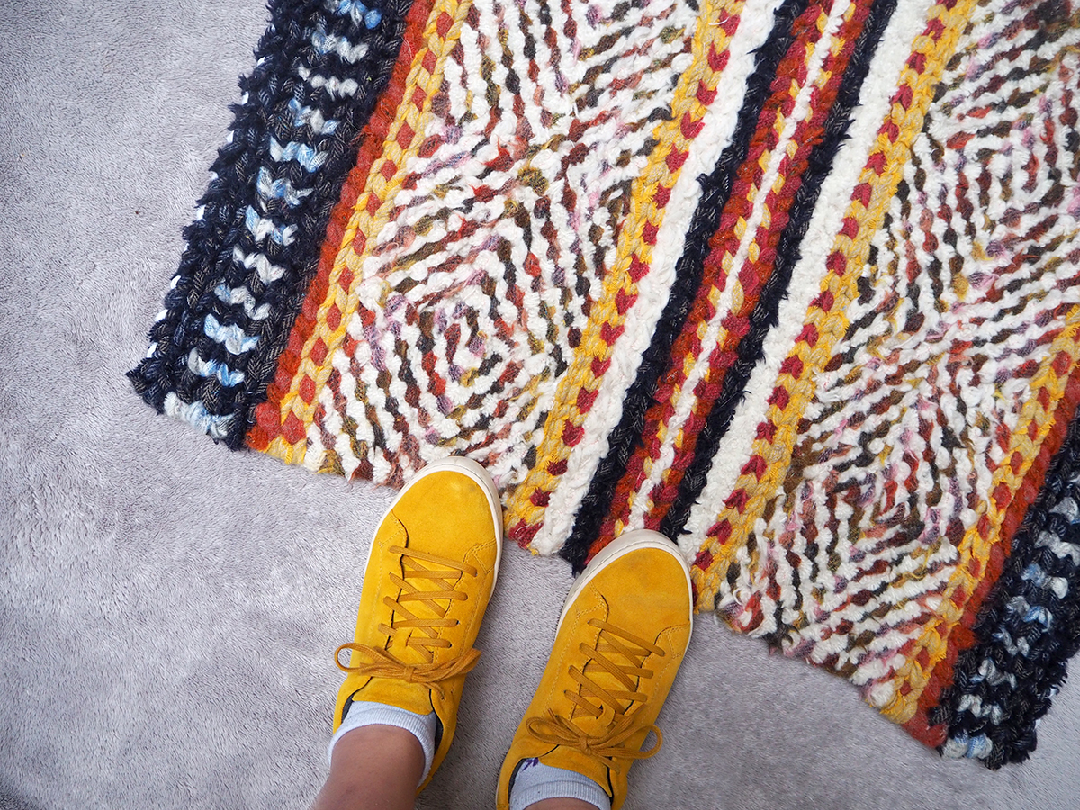 Yellow shoes with handmade twined rug on floor