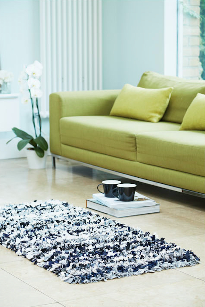 Black and white shaggy rag rug in front of green sofa with coffees