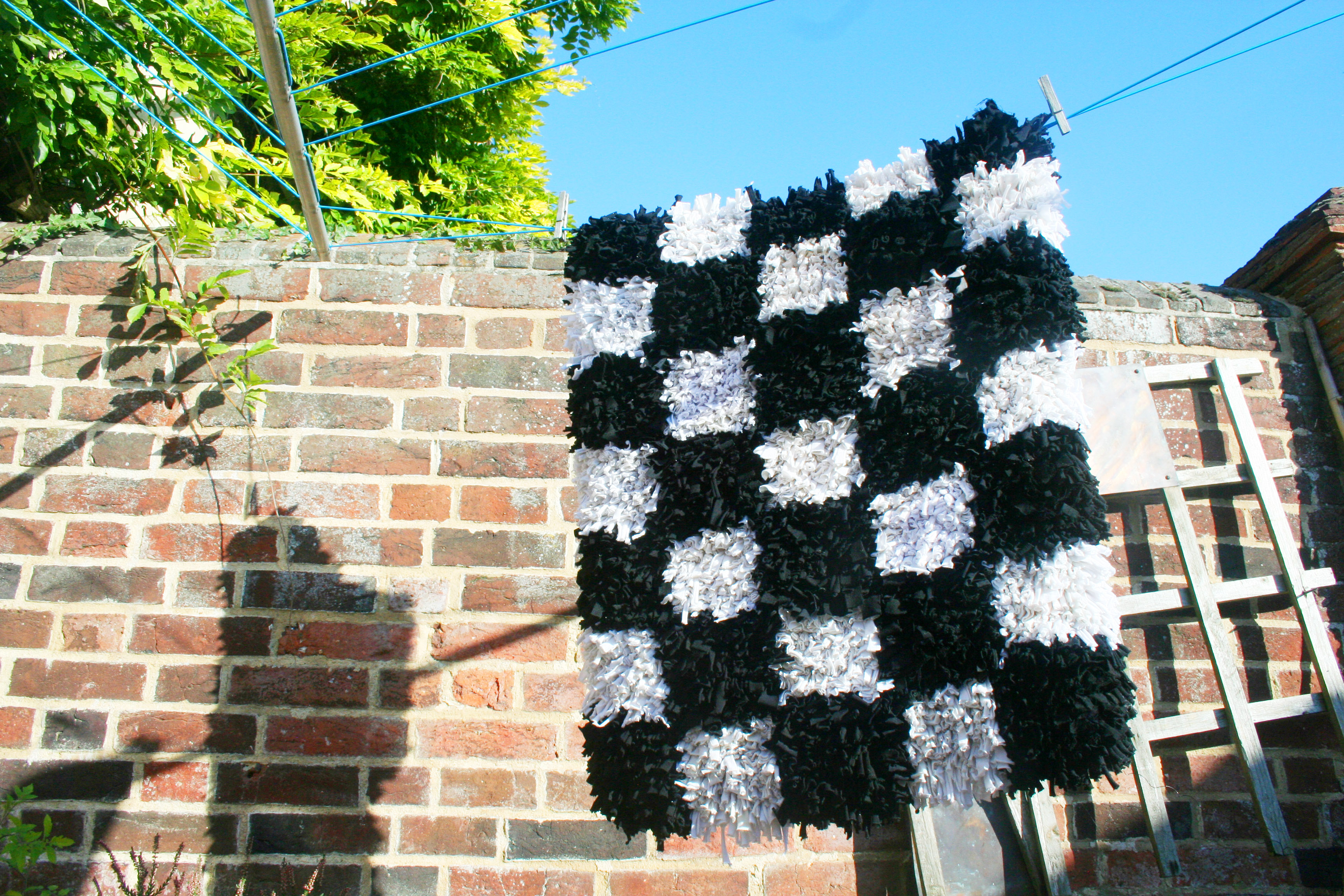 How to clean a rag rug - black and white checked rag rug hanging out to dry on a washing line
