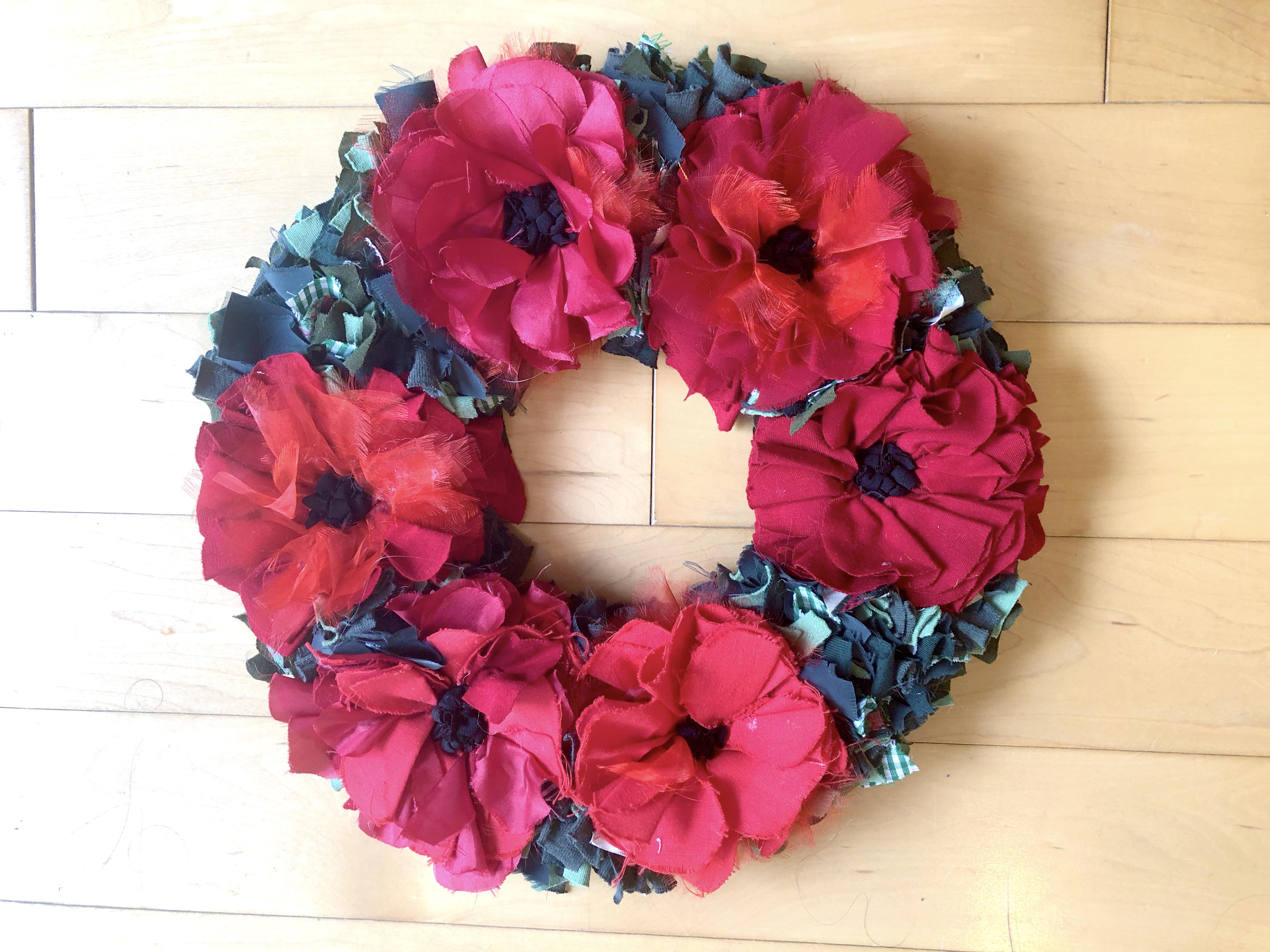 Remembrance day rag rug poppy wreath made using recycled textile waste. Red poppies with green fabric in between. 