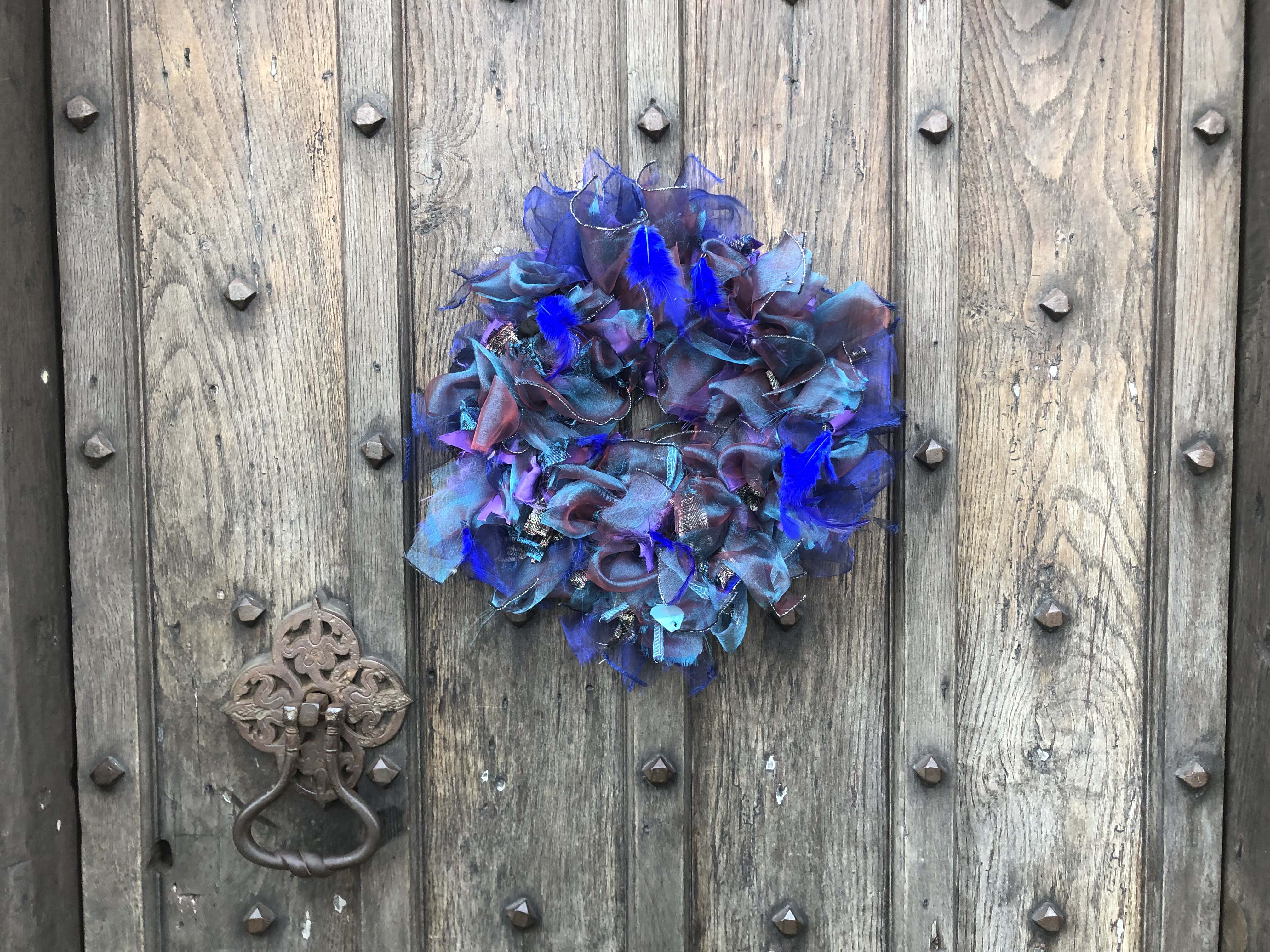 Purple and blue upcycled rag wreath made using an old halloween costume with feathers and shiny voile. 