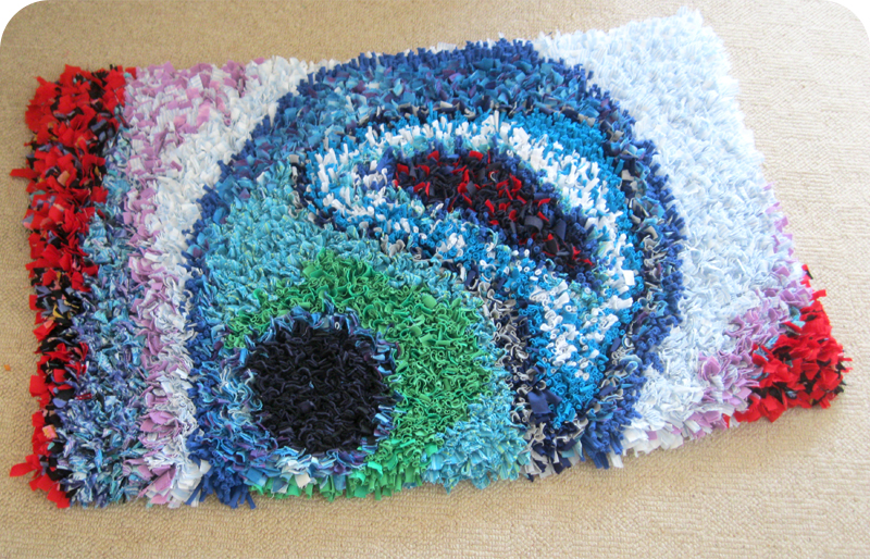 Abstract swirl rag rug with blues, greens and reds made in the proggy technique using old t-shirts