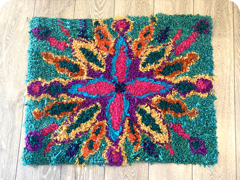 Colourful handmade rag rug with star pattern in recycled sari silk ribbon