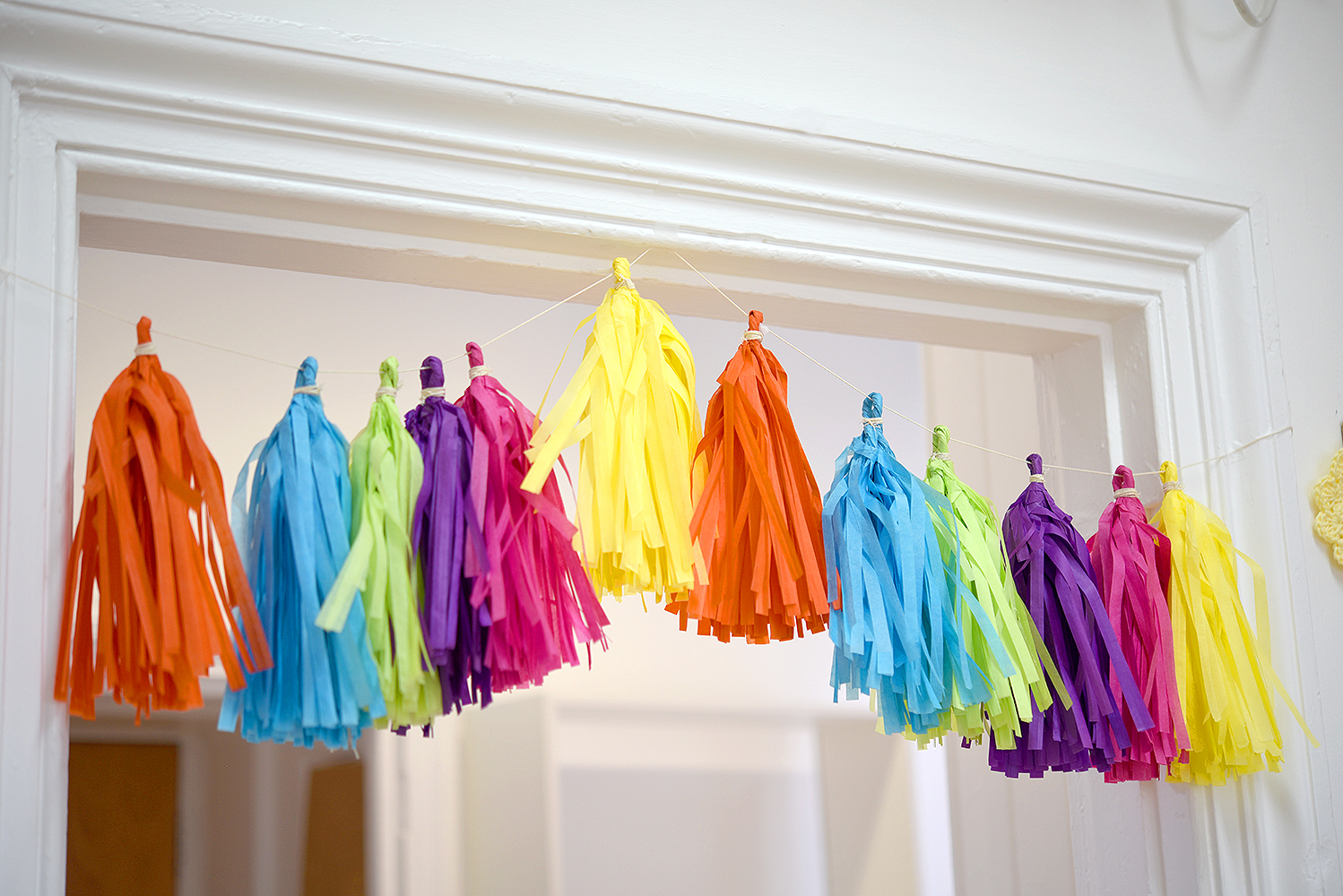 Multi-coloured Handmade Paper Tassels hanging above the door at Tea and Crafting's new workshop space