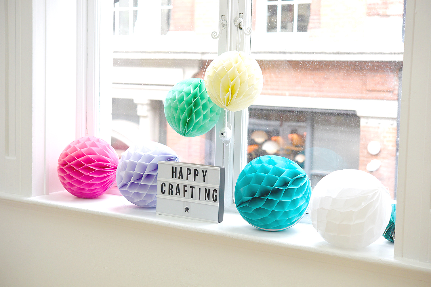 Paper lanterns in front of the large window with happy crafting lightbox