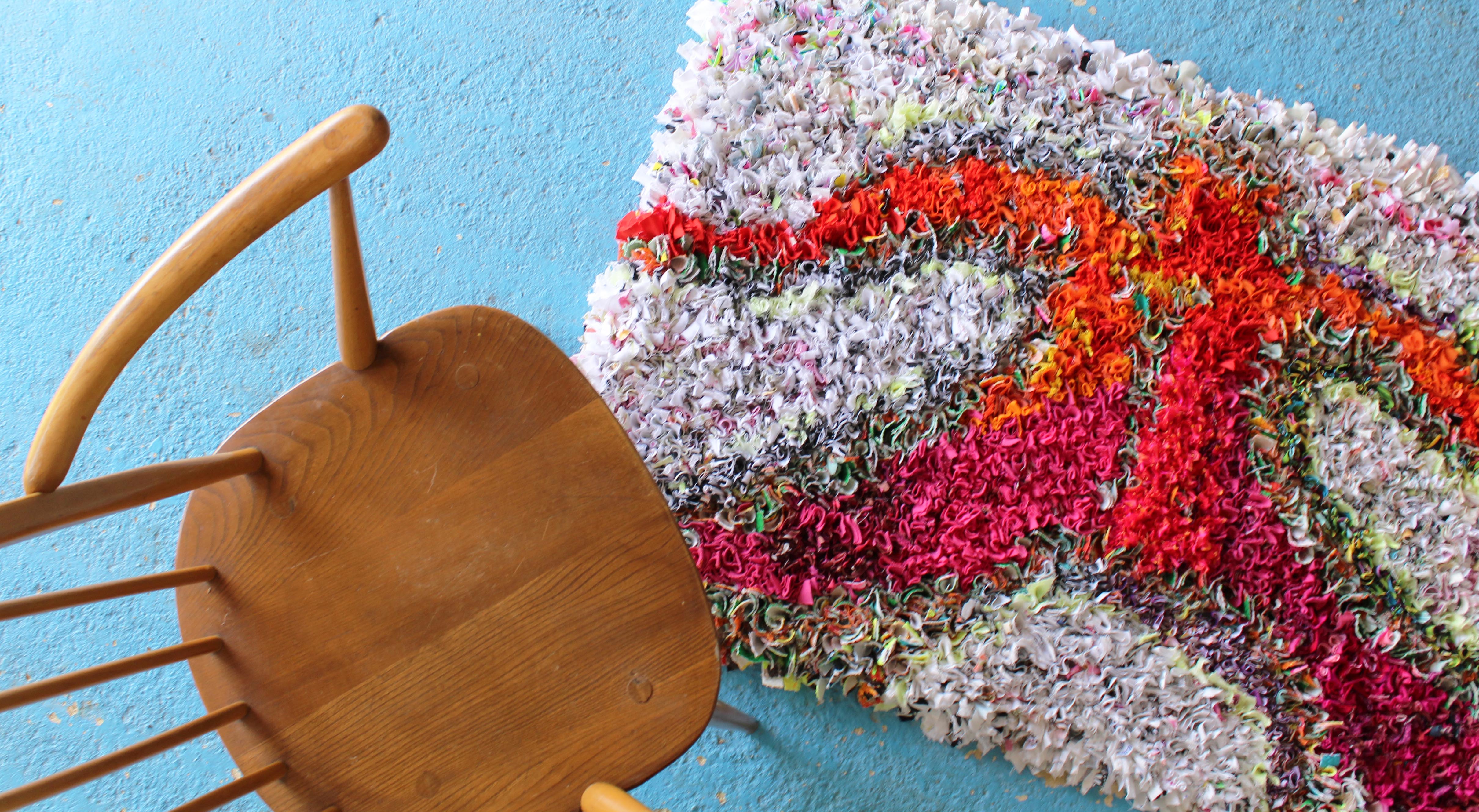 A Ragged Life rag rug on a blue floor with a wooden Ercol chair