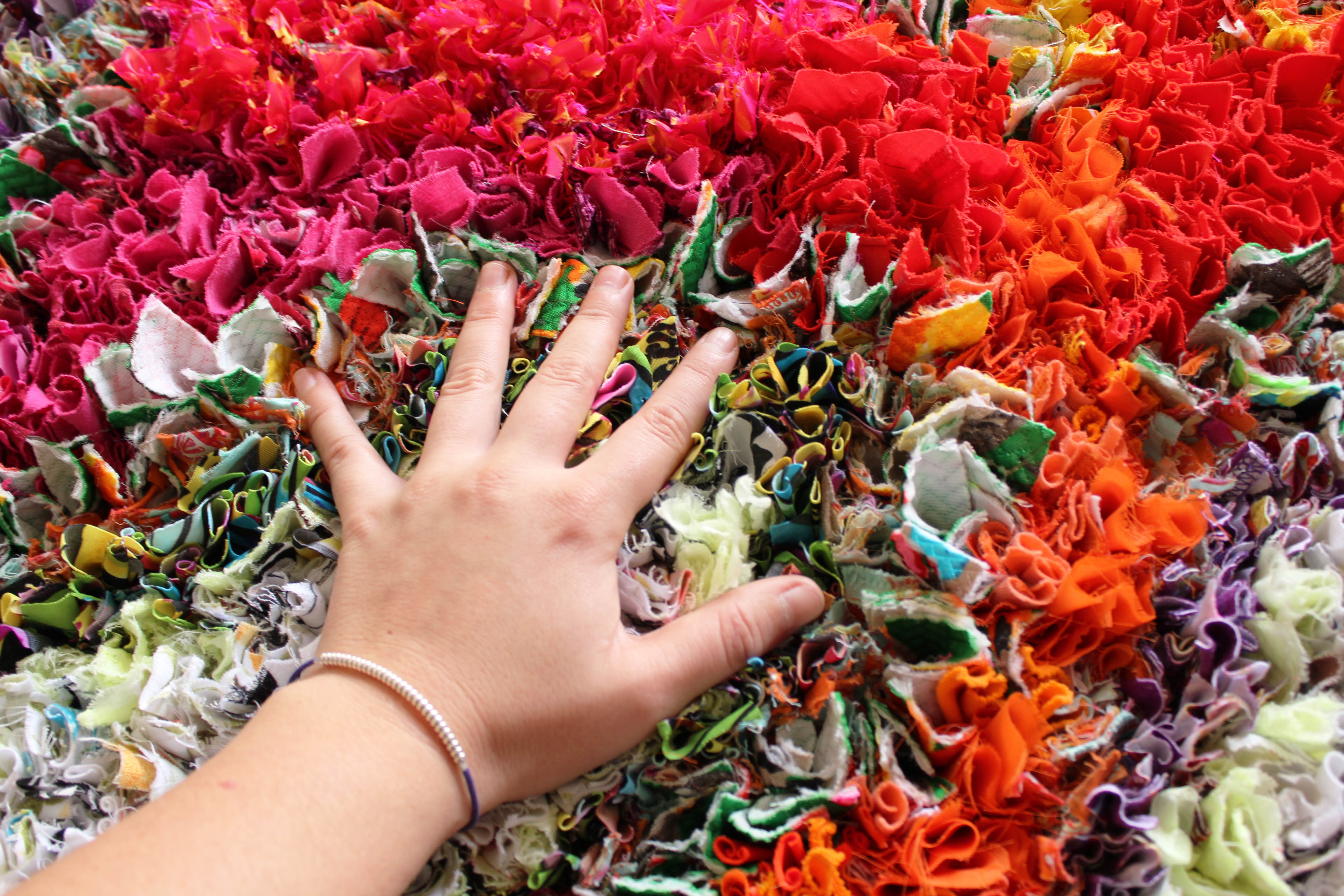 A hand sinking into the soft rags of a handmade rag rug 