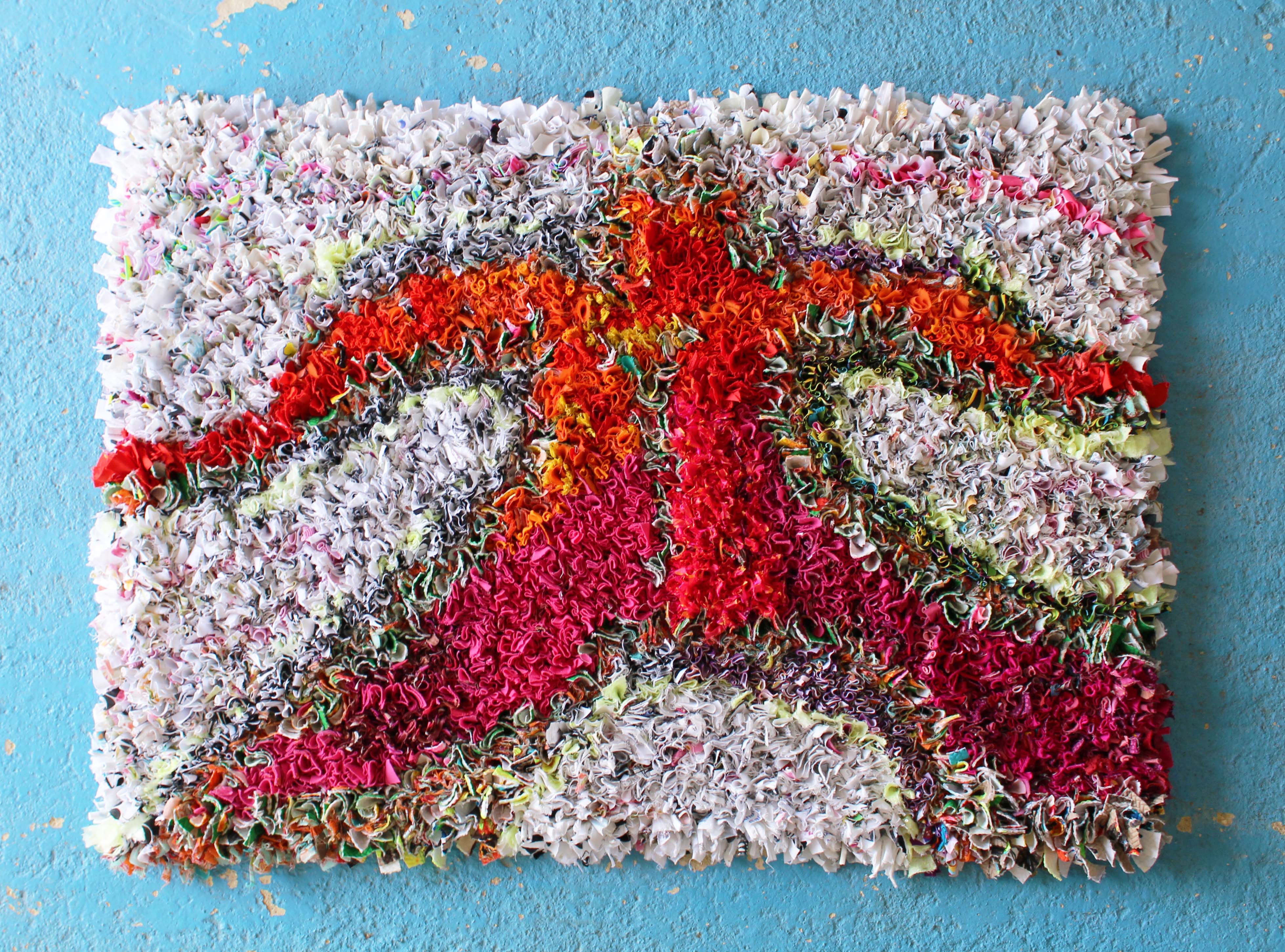 Beautiful rag rug shaped like a person in the shaggy rag rugging technique with orange and pink