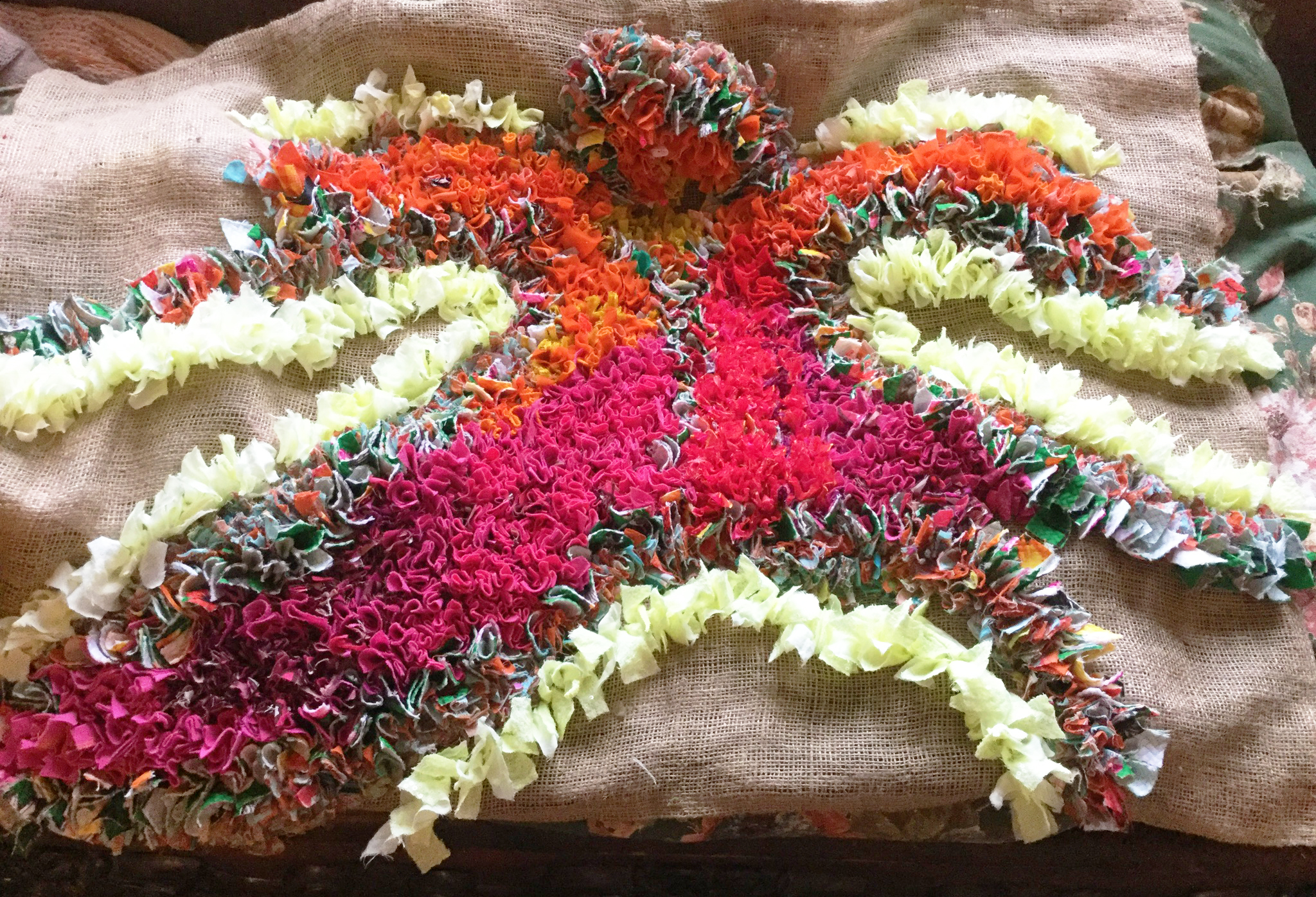 A half made beautiful rag rug with pink orange done in the proggy style