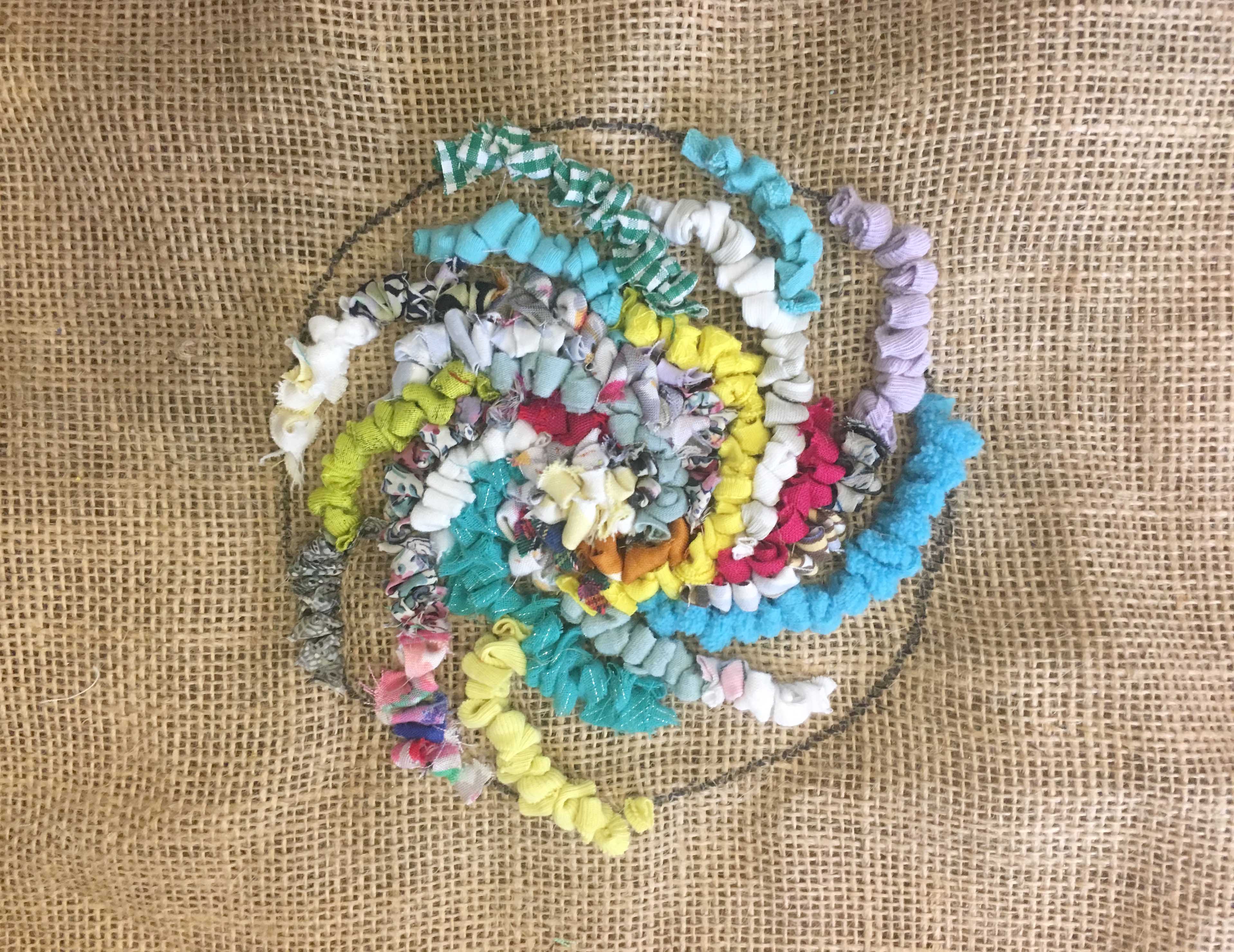 Multicoloured loopy rag rug swirl on hessian