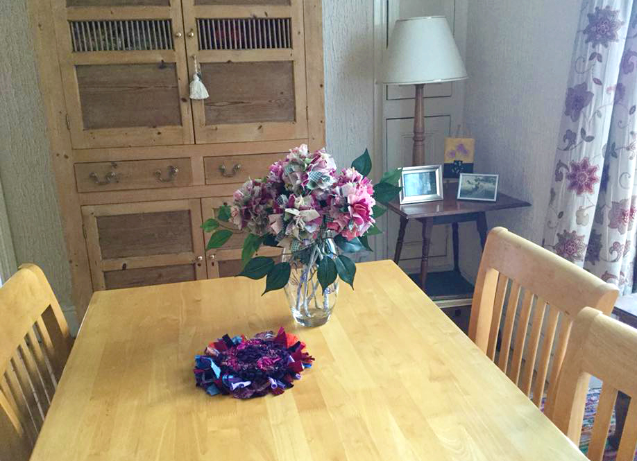 Cotton rag rug flowers in a bouquet on a table with a rag rug trivet