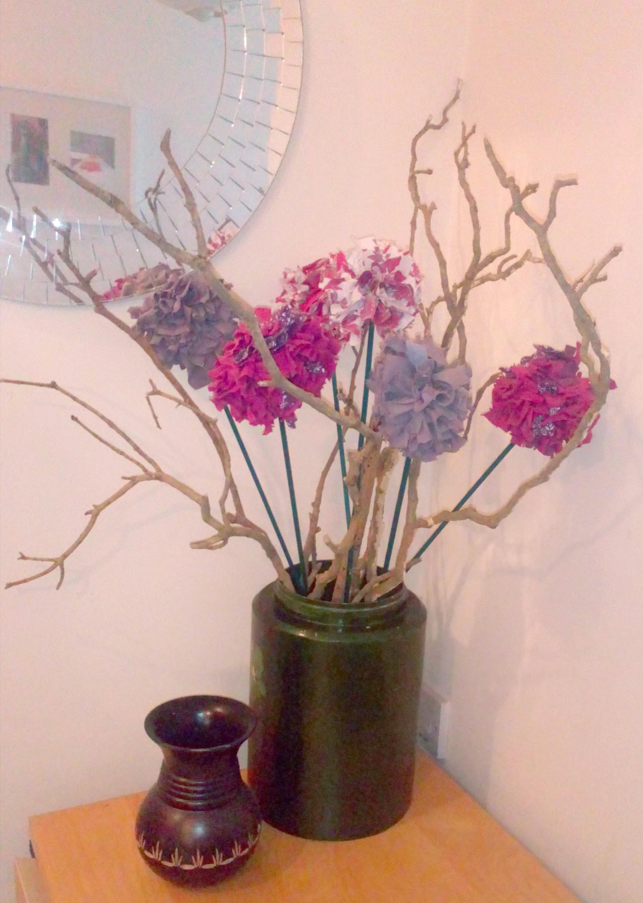 Pink fabric flowers in a green vase with wooden twigs