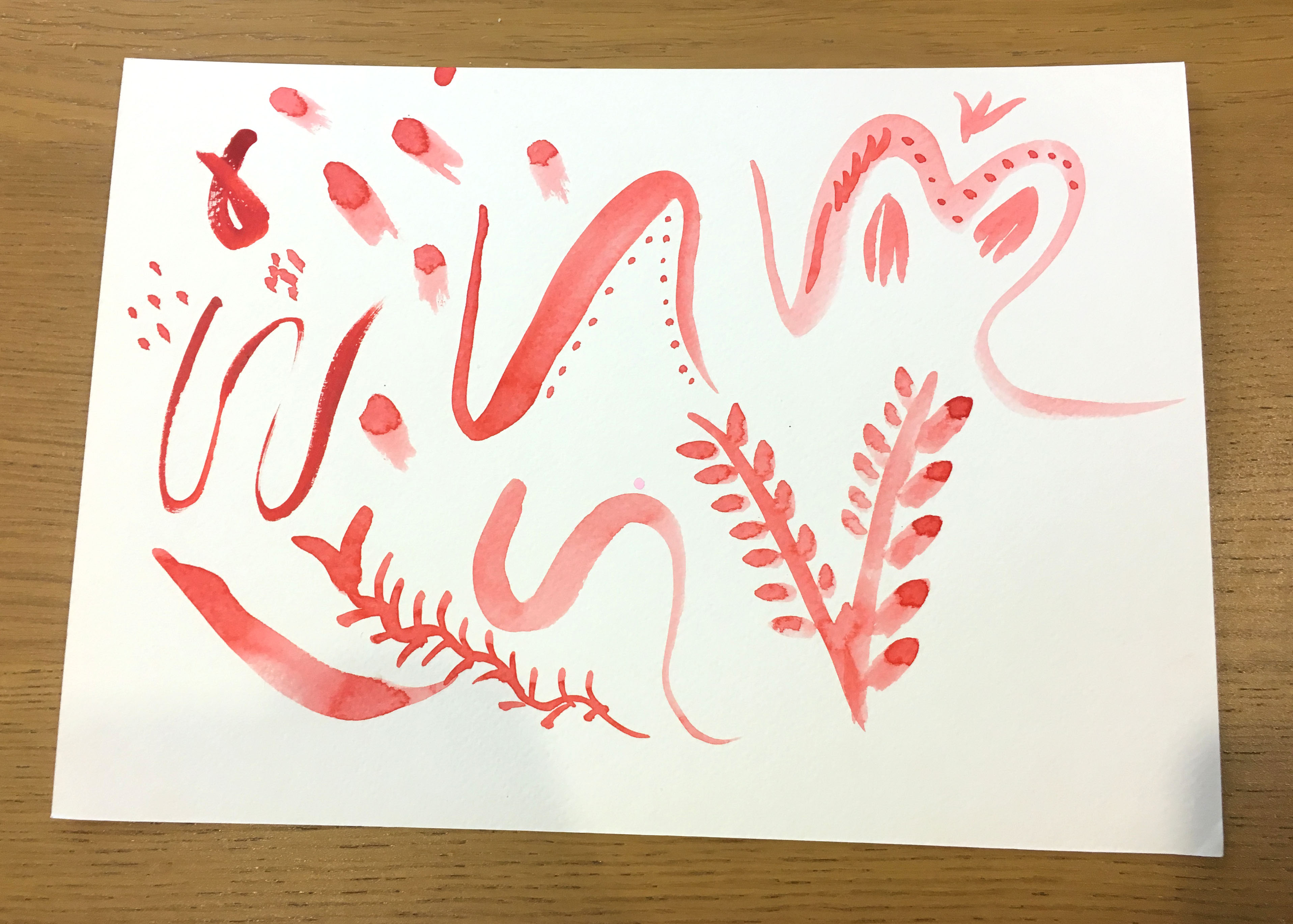 Watercolour practice paper with red doodles on.