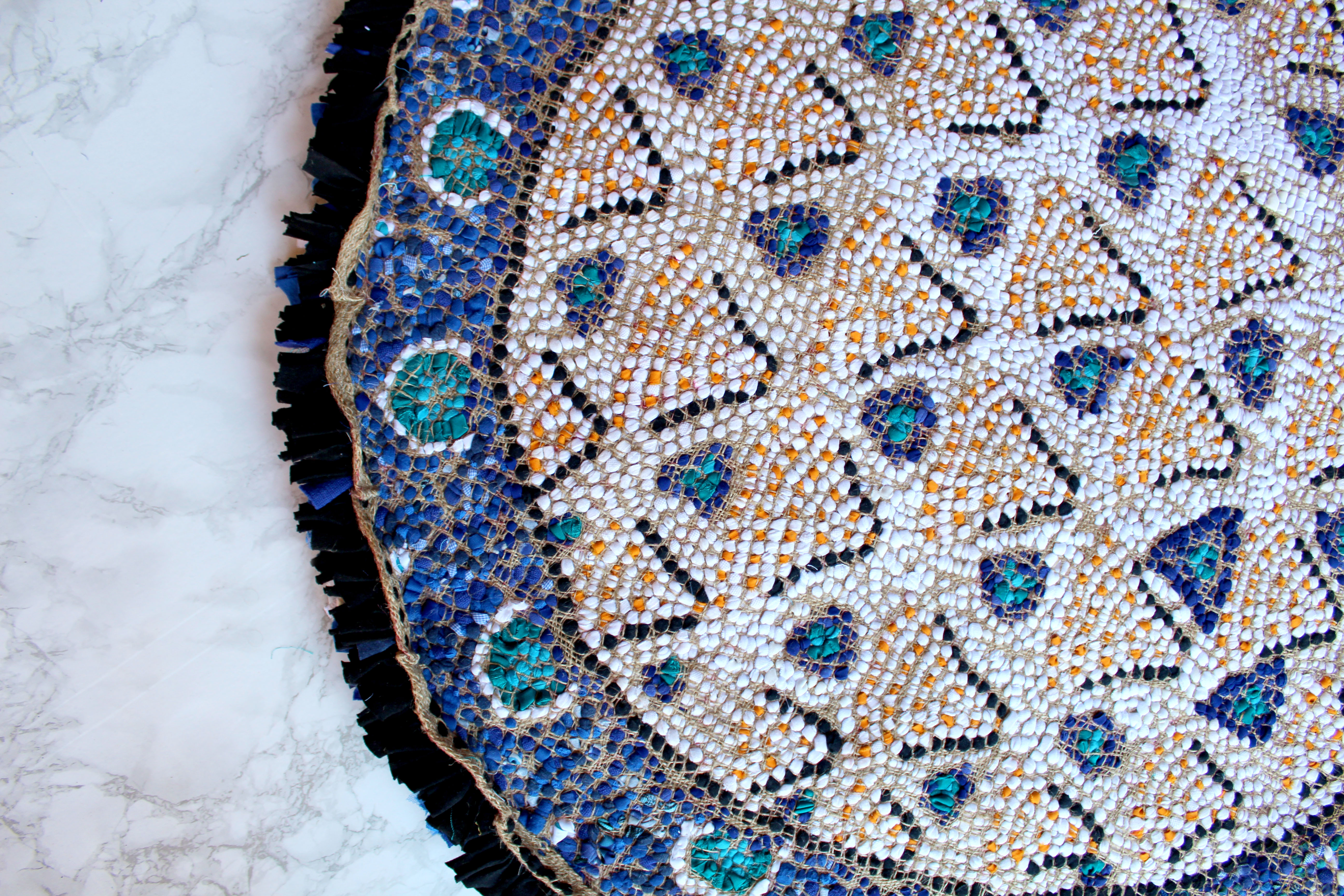 Circular rag rug based on an Iznik plate design with blue, white and orange. Back of rag rug