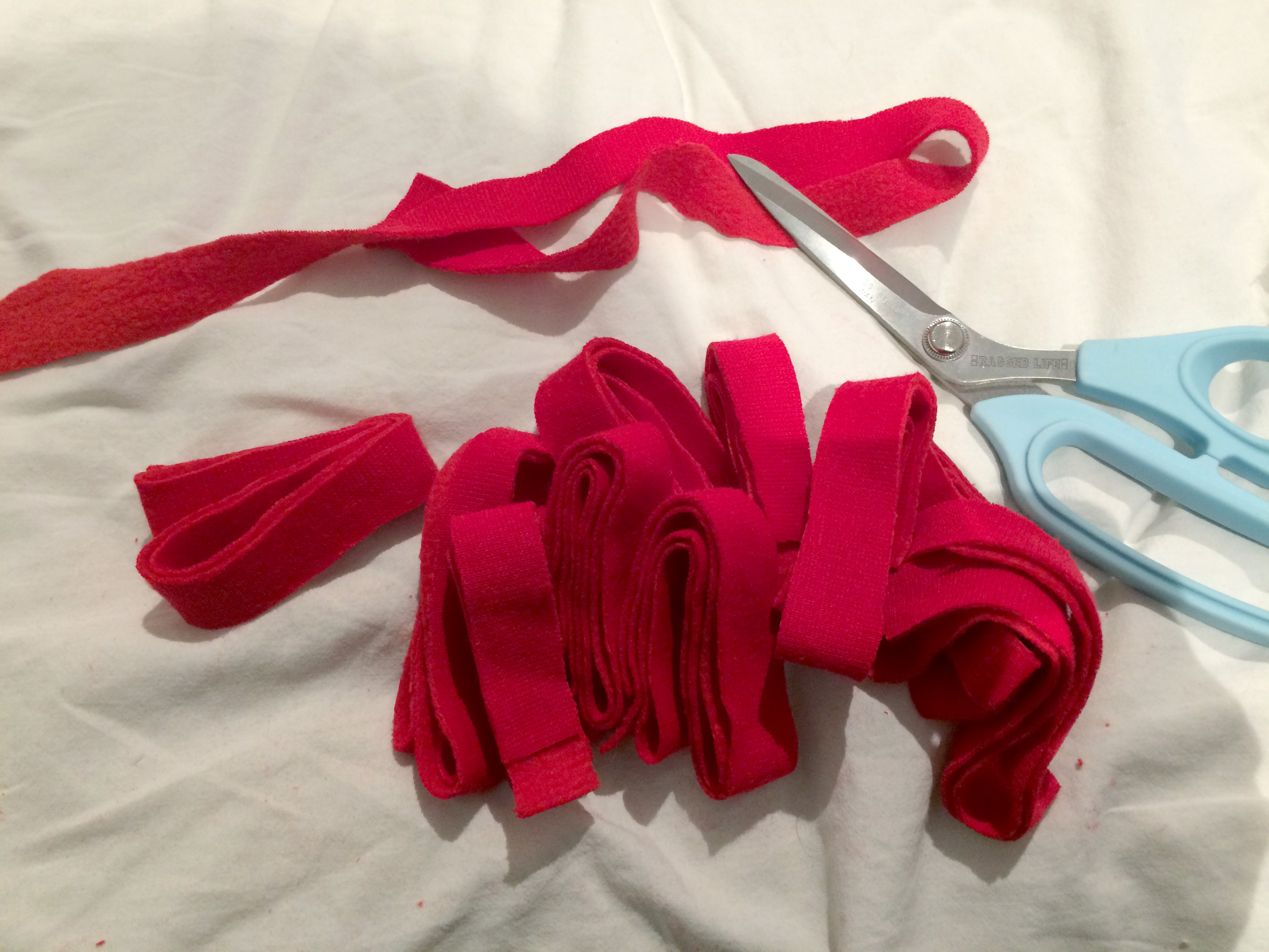 Cutting up red fabric in bed