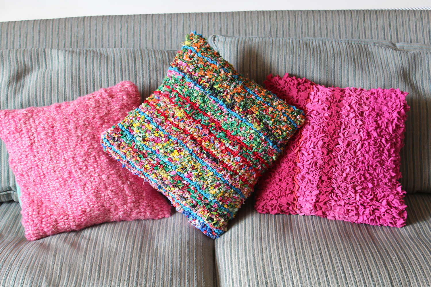 Pink and colourful hooked rag rug cushions on sofa
