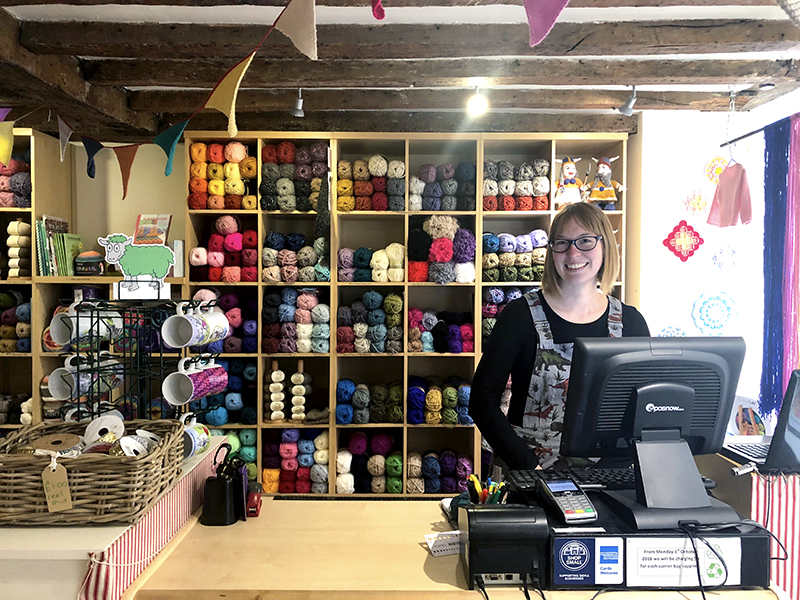 Knit and Stitch York craft shop till with shelves of wool behind