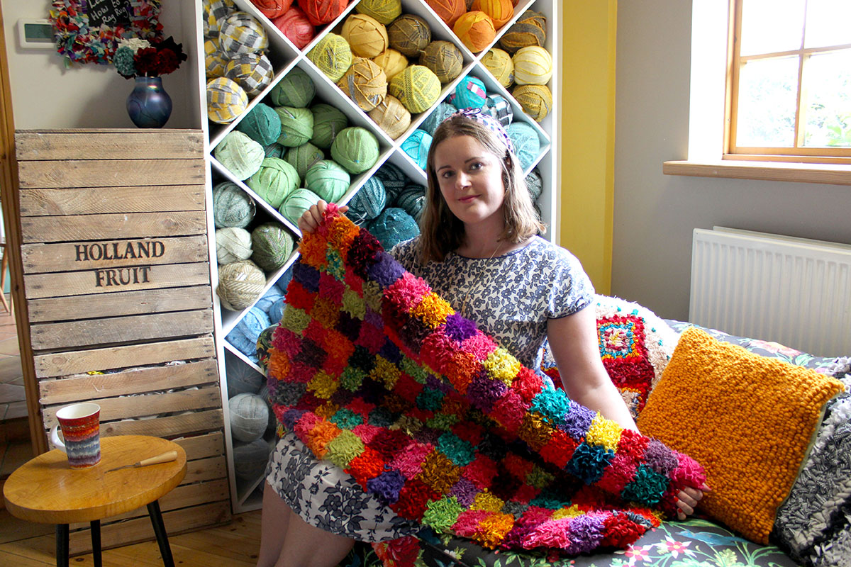 Elspeth Jackson making a rag rug in front of her wall of 100% wool blanket yarn