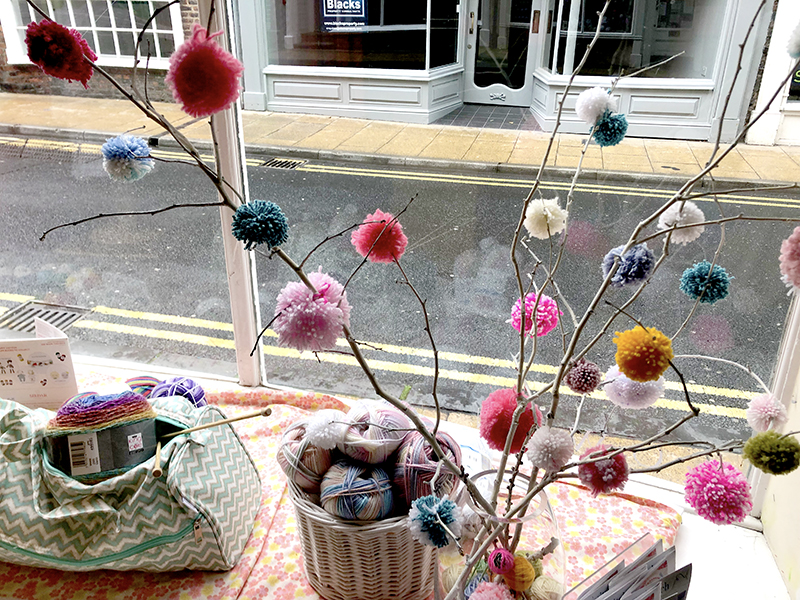 Pom poms in window display at Knit and Stitch in central York