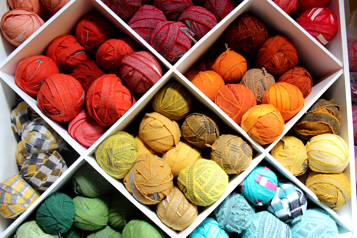 Red, orange and yellow blanket yarn for rag rugging stacked into custom made craft shelving