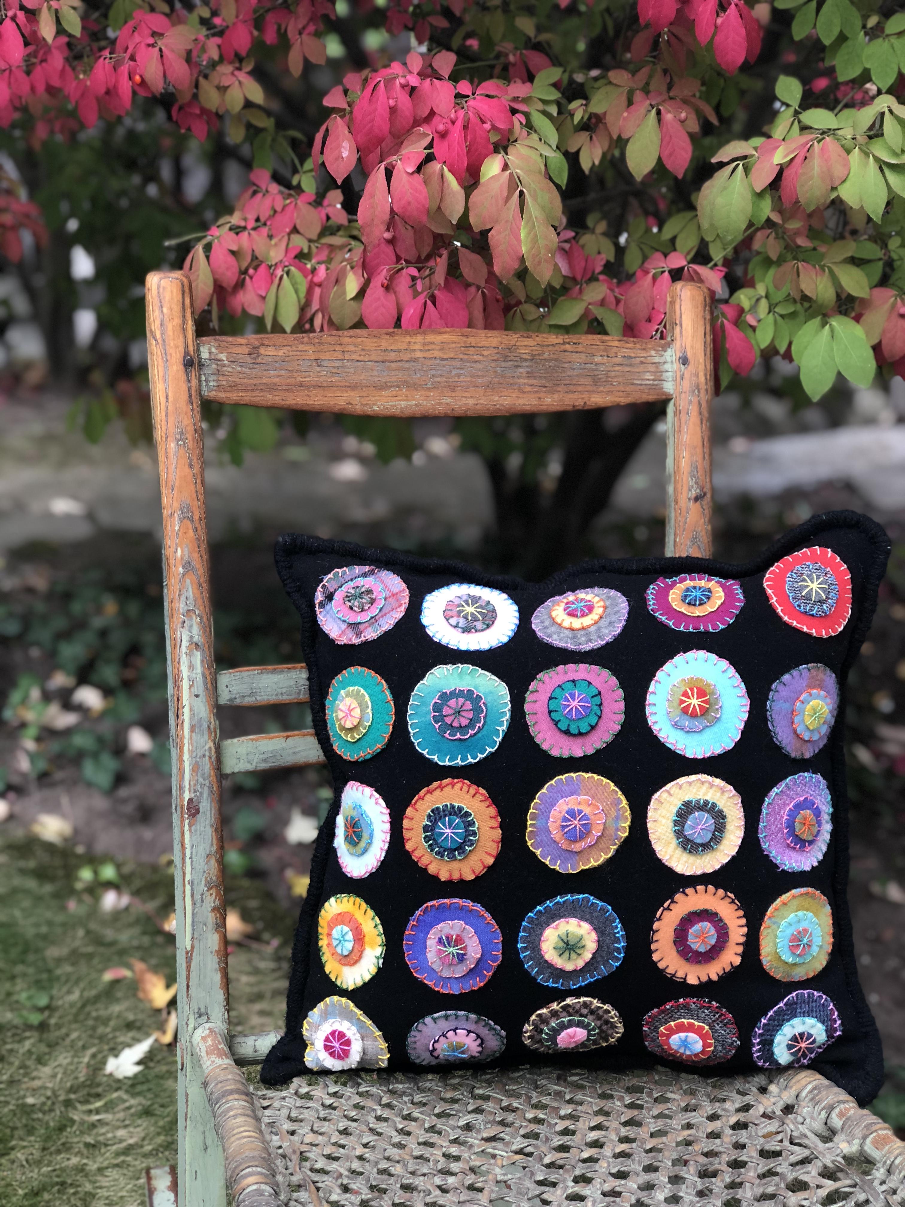 A black cushion with colourful circle pieces of fabric stitched onto it by Yvonne Iten-Scott.