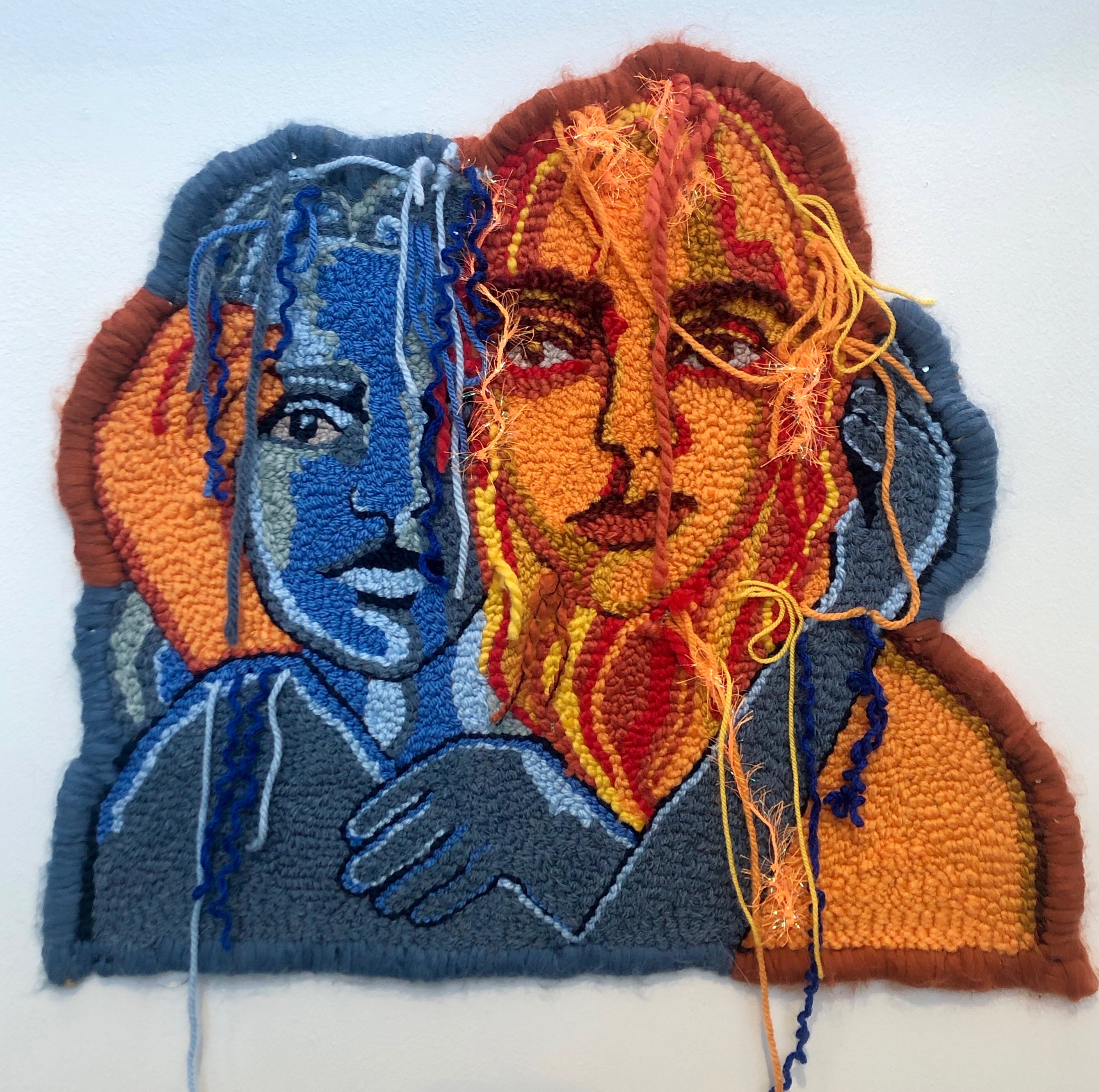 textile art by Selby Hurst Inglefield of 2 people, one in blues and the other in yellow and orange tones