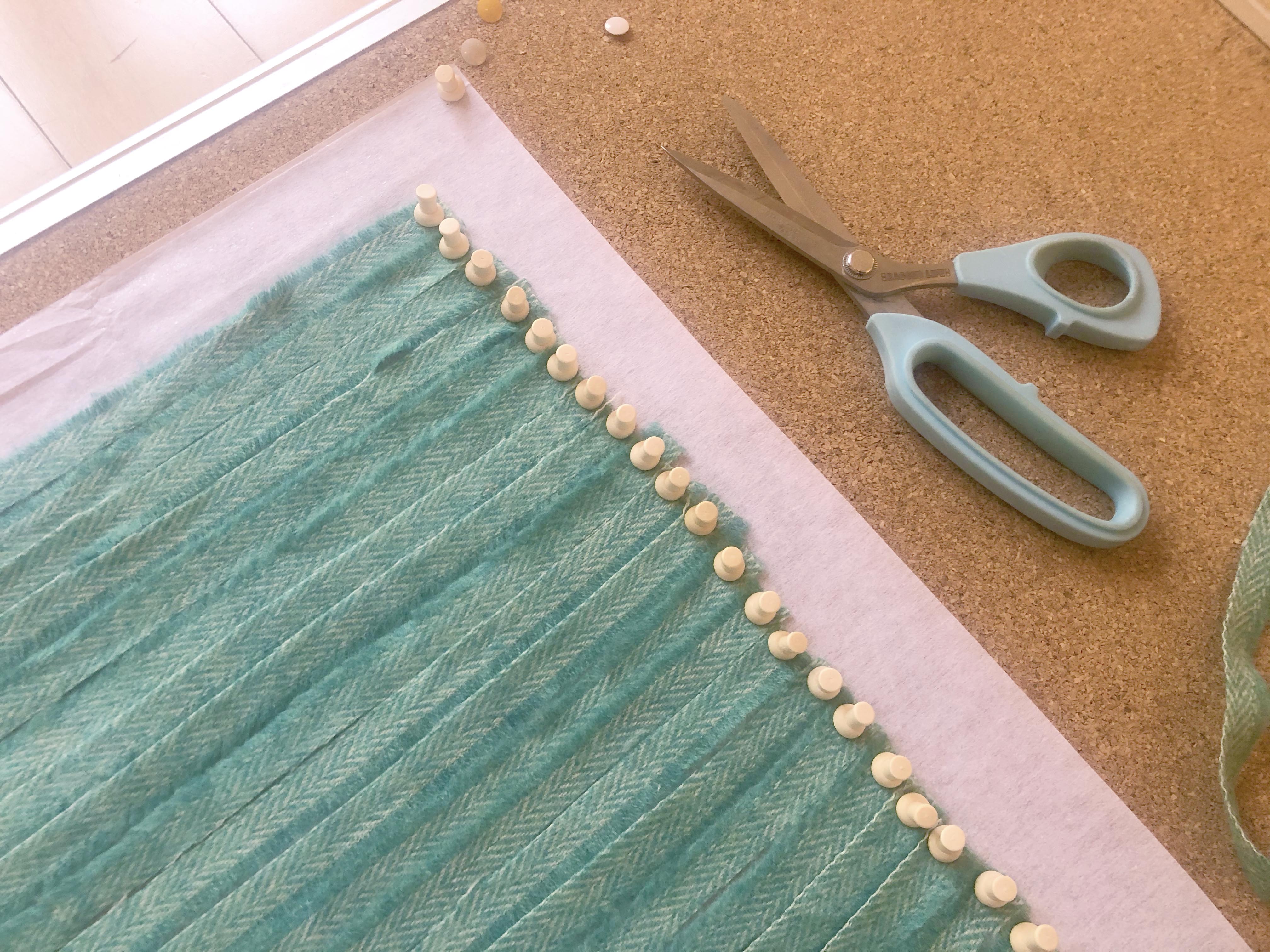 Strips of blanket yarn pinned to cork board