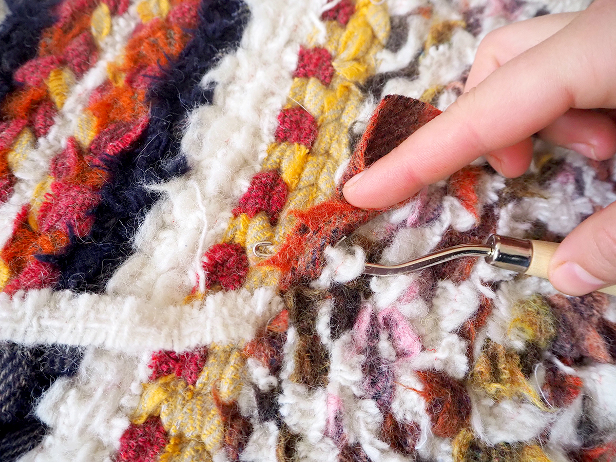 Using a latch hook to sew in the ends of a twined rag rug