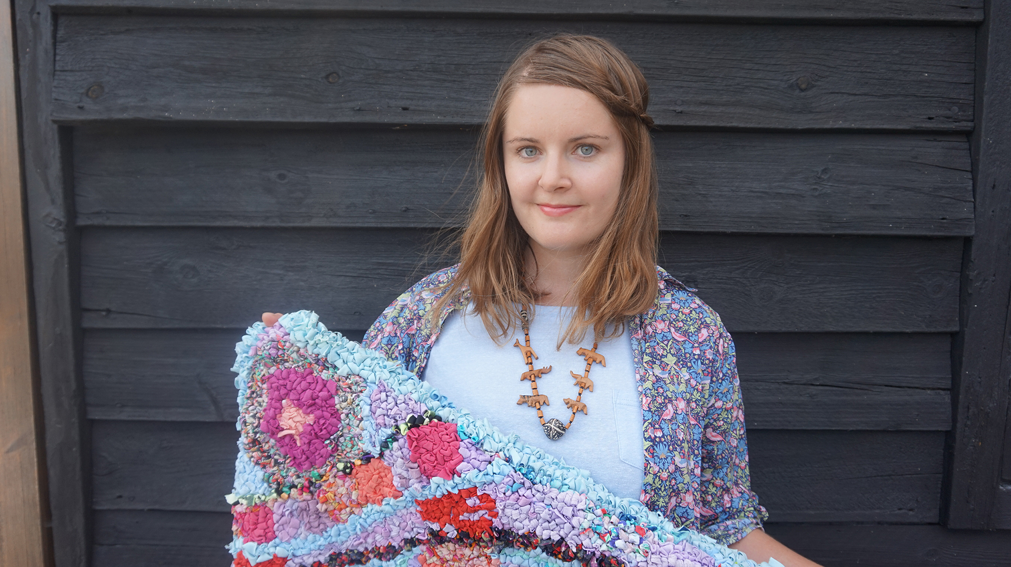 elspeth holding shaggy rag rug in front of wall
