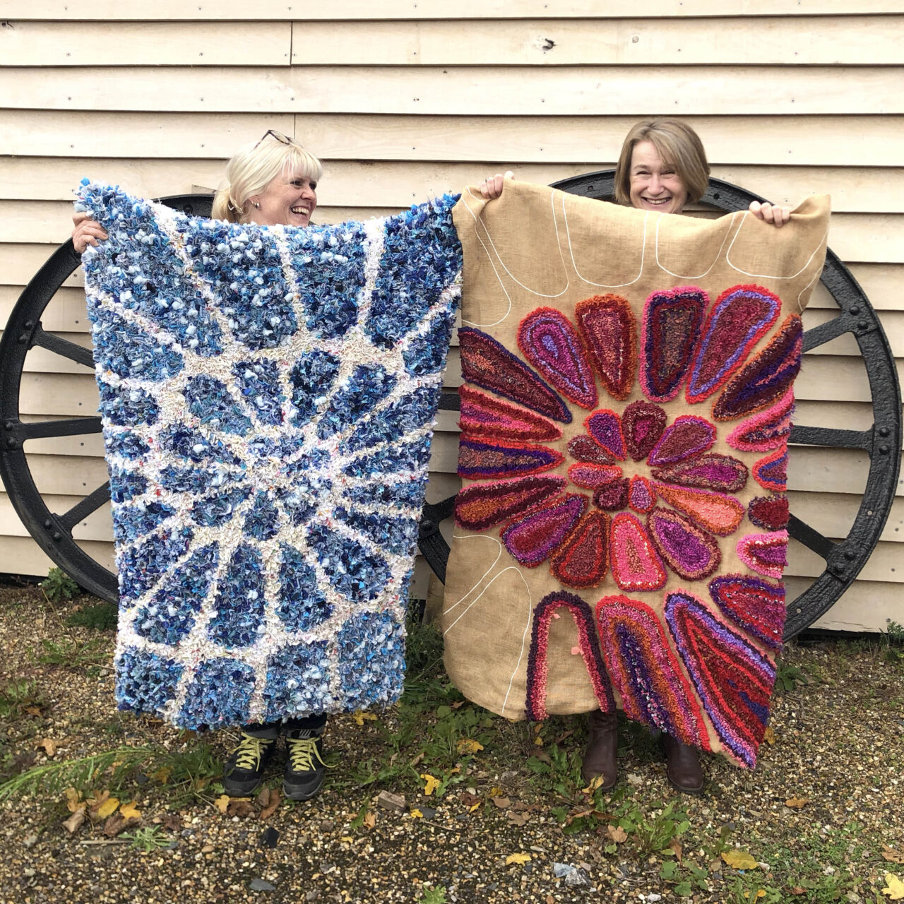 Cherry and Sany holding work in progress spiral design short shaggy rag rugs on pre-printed rag rug hessian